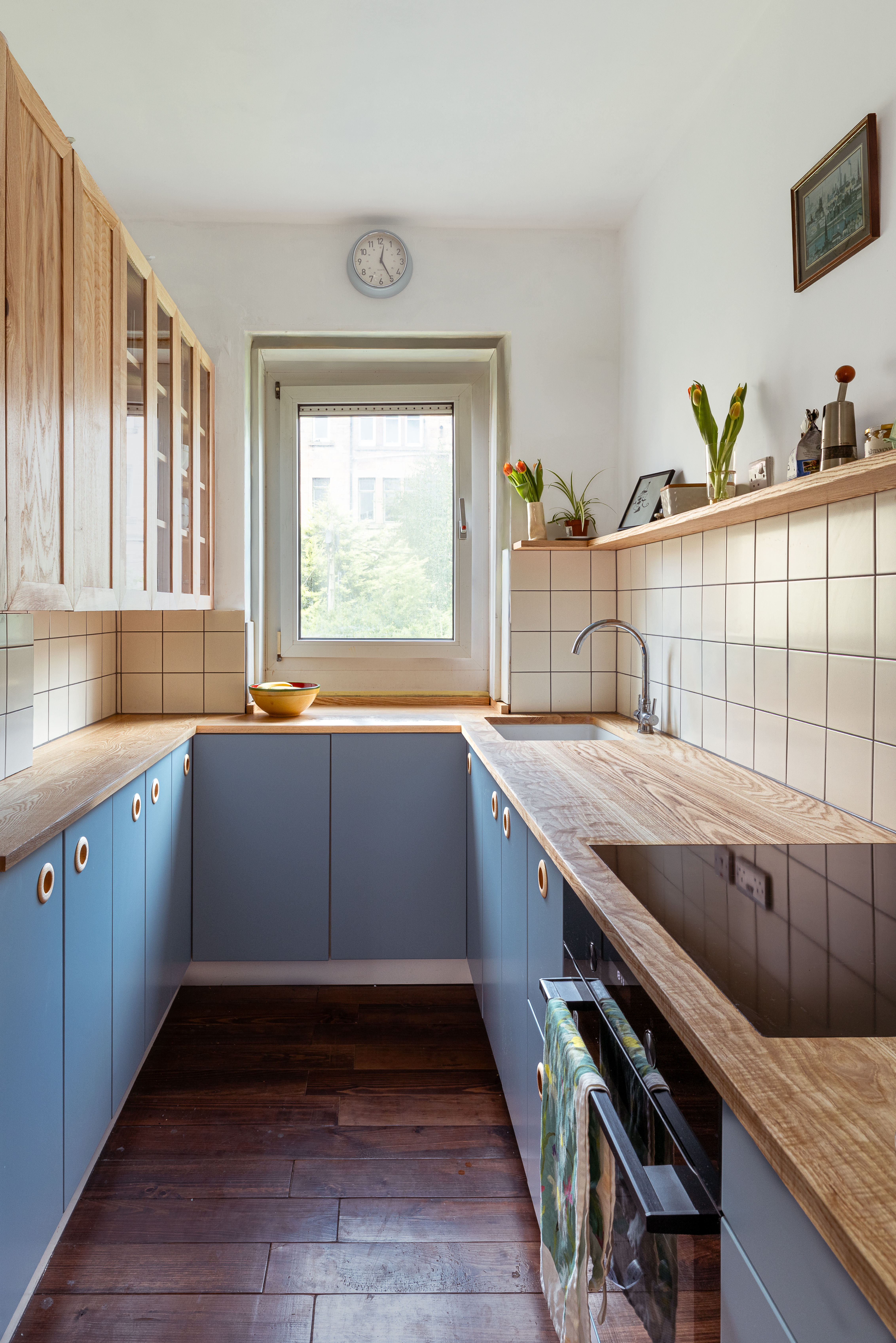 Bespoke galley kitchen with blue cabinetry and ash worktops and hanging cabinets